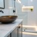Modern bathroom vanity with honed Calacatta marble countertop and a bronze hand-hammered sink, lit by soft natural light.